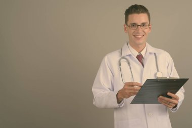 Gri arka planda genç, yakışıklı doktor.