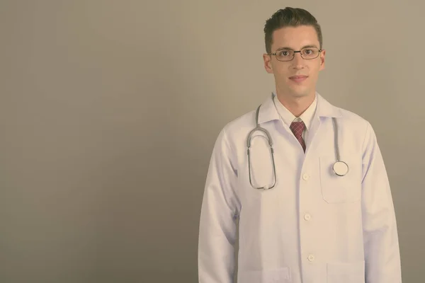 Молодой красивый мужчина врач на сером фоне — стоковое фото