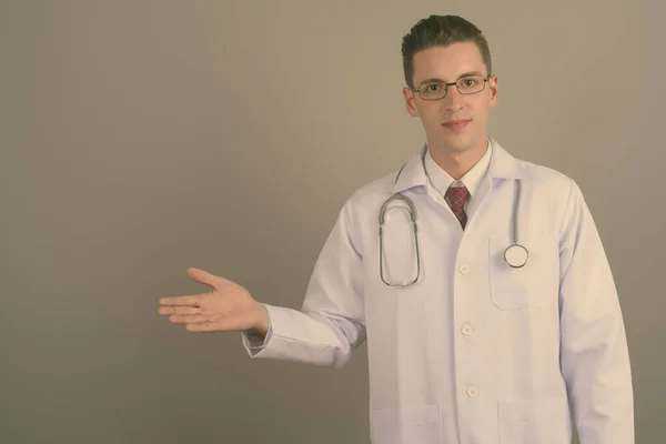 Joven hombre guapo médico contra fondo gris — Foto de Stock