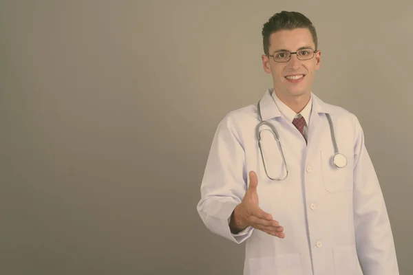 Joven hombre guapo médico contra fondo gris —  Fotos de Stock