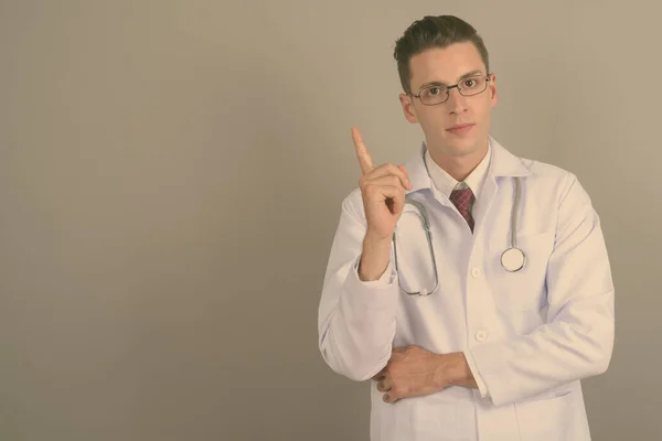 Молодий красивий чоловік лікар на сірому фоні — стокове фото