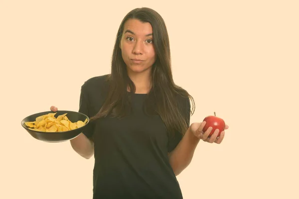 Молодая белая женщина с миской картофельных чипсов и красным яблоком — стоковое фото
