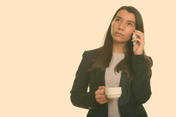 Denkende jonge blanke zakenvrouw praten op mobiele telefoon terwijl het houden van koffie kopje — Stockfoto