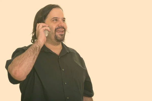 Счастливый жирный кавказский мужчина улыбается и отворачивается, разговаривая по мобильному телефону — стоковое фото