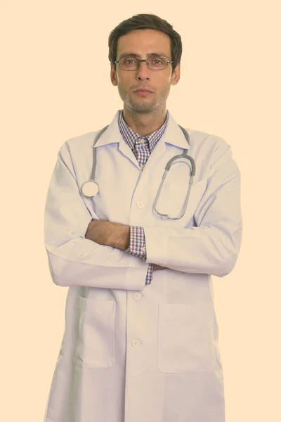 Studio shot of young handsome man doctor wearing eyeglasses with arms crossed — Stock Photo, Image