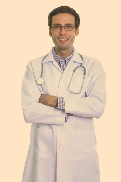 Студійний знімок молодого щасливого лікаря, який посміхається під час носіння окулярів з схрещеними руками — стокове фото