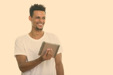Dijital tablet tutarken gülümseyen düşünceli, genç, mutlu Afrikalı adam.