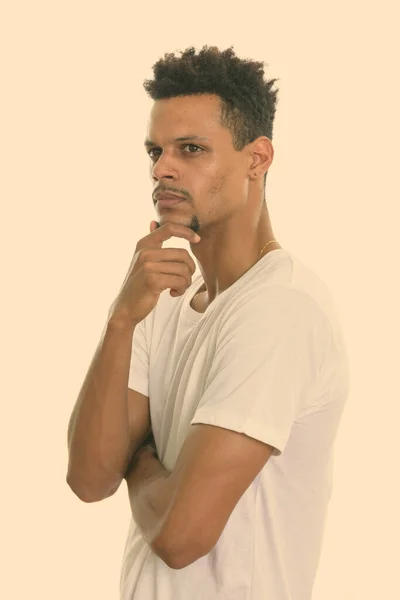 Studio shot of young African man thinking while looking to the side — Stock Photo, Image