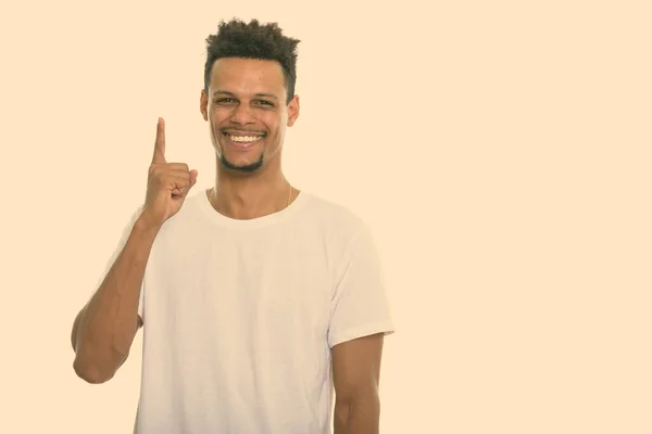 Estúdio tiro de jovem feliz homem africano sorrindo enquanto apontando o dedo para cima — Fotografia de Stock