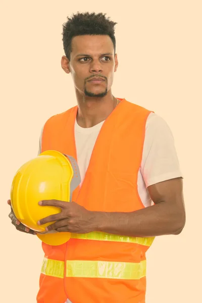 Joven trabajador africano de la construcción sosteniendo casco de seguridad mientras piensa —  Fotos de Stock