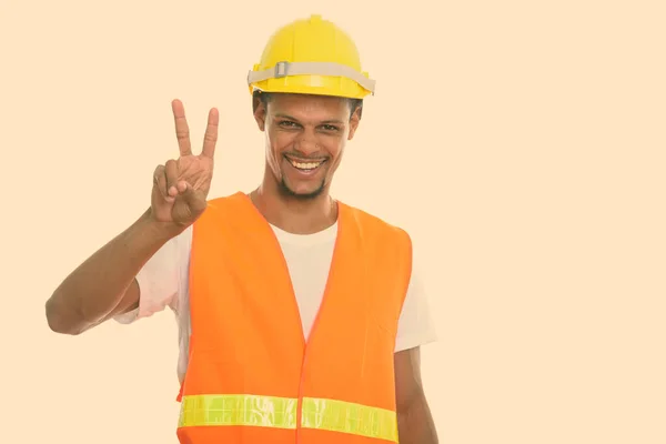 Młody szczęśliwy Afrykanin budowlany pracownik uśmiecha się dając znak pokoju — Zdjęcie stockowe
