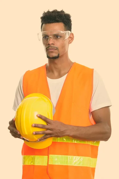 Joven trabajador africano de la construcción sosteniendo casco de seguridad mientras piensa —  Fotos de Stock