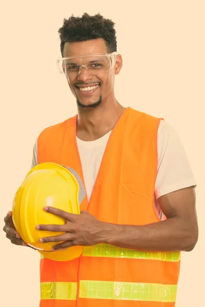 Bedachtzame gelukkige Afrikaanse man bouwvakker glimlachen terwijl het houden van de veiligheid helm — Stockfoto