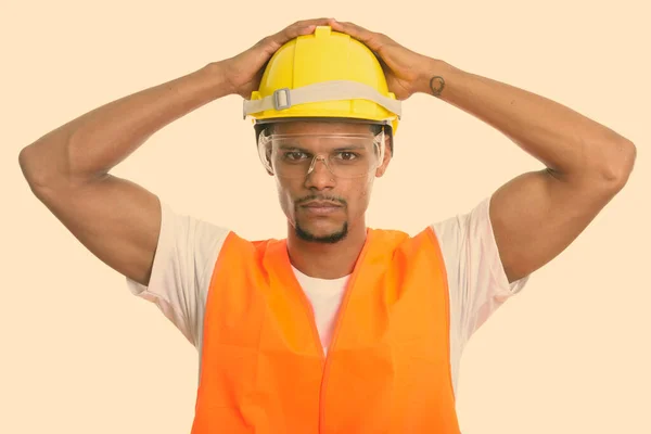 Joven trabajador africano de la construcción con ambas manos en el casco de seguridad —  Fotos de Stock