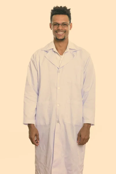 Estudio disparo de joven feliz africano hombre médico sonriendo mientras está de pie —  Fotos de Stock