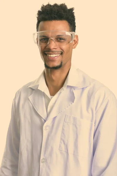 Studio shot of young happy African man doctor smiling while wearing protective glasses — Stock Photo, Image