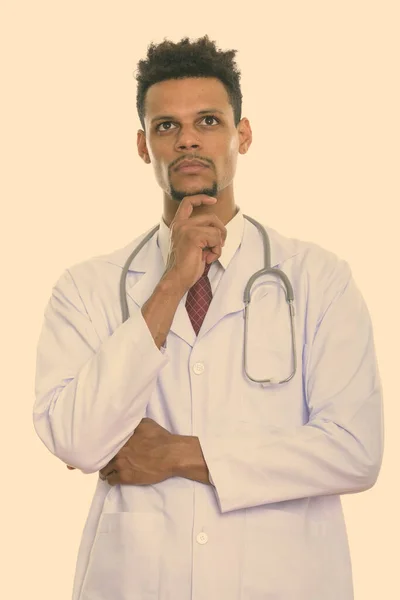 Studio shot of young African man doctor thinking while looking up — Stock Photo, Image