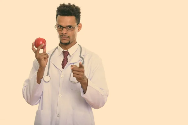 Joven africano médico sosteniendo manzana roja mientras apunta a la cámara —  Fotos de Stock