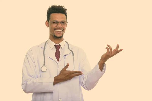 Fiatal boldog afrikai férfi orvos mosolyog, miközben mutat valamit — Stock Fotó