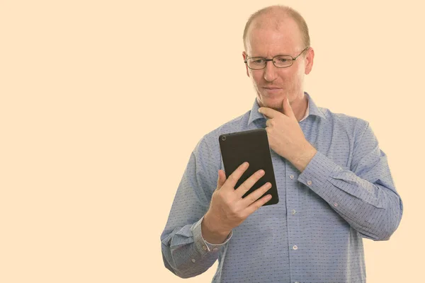 Студийный снимок бизнесмена, держащего цифровой планшет, думая: — стоковое фото