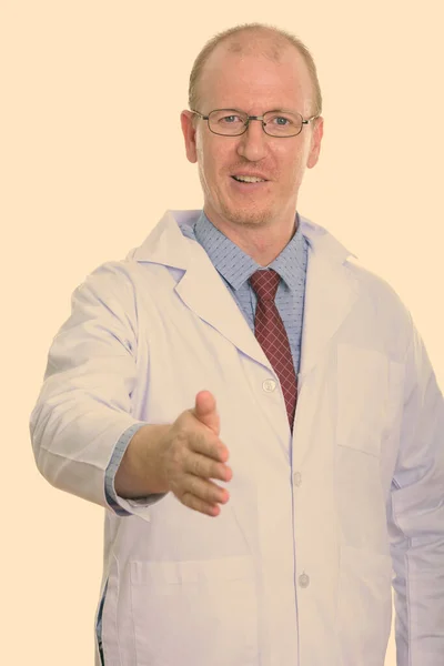 Estúdio tiro de homem feliz médico sorrindo ao dar aperto de mão — Fotografia de Stock