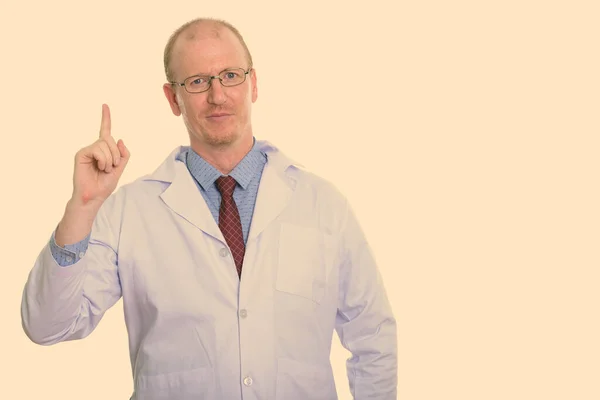 Студійний знімок лікаря-чоловіка, який вказує пальцем вгору — стокове фото
