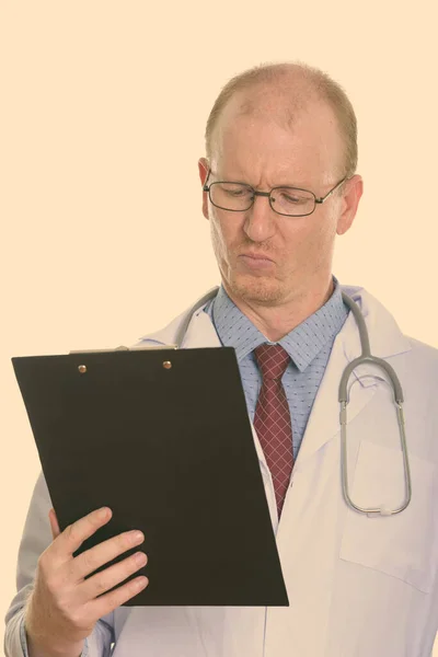 Studio shot of man doctor reading on clipboard — Stock Photo, Image