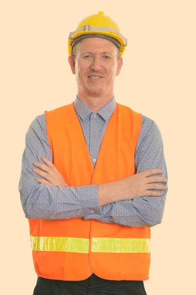 Estúdio tiro de homem feliz trabalhador da construção sorrindo com os braços cruzados — Fotografia de Stock