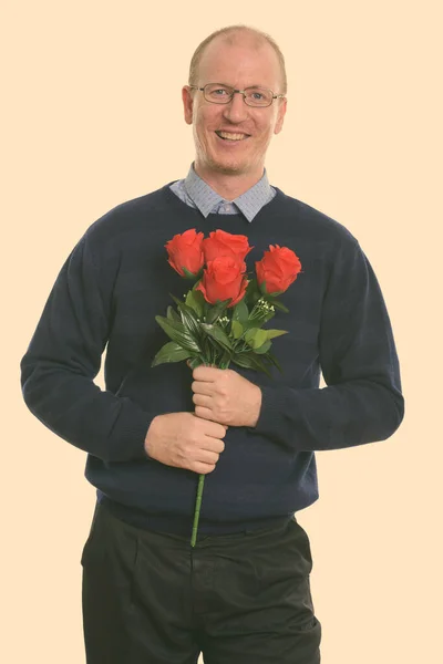 Studio záběr šťastný muž usmívá, zatímco drží červené růže připravené na Valentýna — Stock fotografie