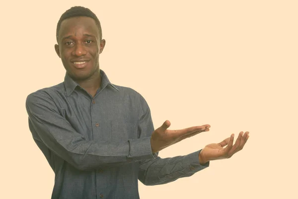 Joven hombre africano feliz sonriendo y mostrando algo — Foto de Stock