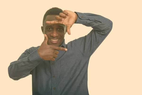 Genç mutlu Afrikalı adam gülümsüyor ve parmaklarıyla odaklanıyor. — Stok fotoğraf