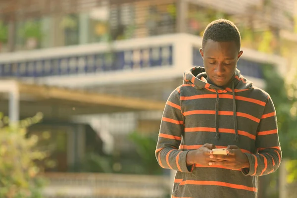 Young African man using mobile phone outdoors — Stock Photo, Image