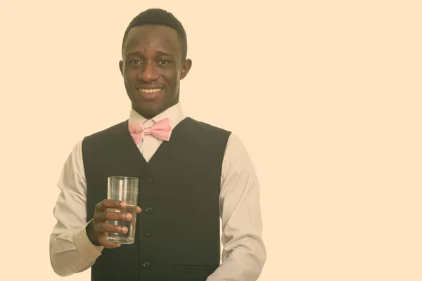 Joven camarero africano feliz sonriendo y sosteniendo un vaso de agua —  Fotos de Stock