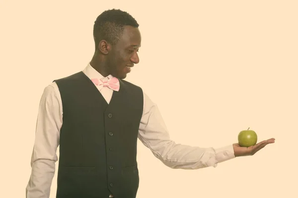 Молодой счастливый африканский официант улыбается и держит зеленое яблоко — стоковое фото