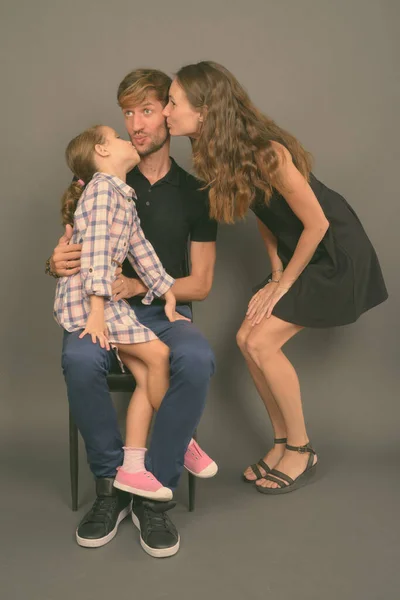 Молода щаслива сім'я з'єднується на сірому фоні — стокове фото