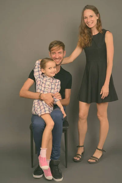 Jong gelukkig familie binding samen tegen grijs achtergrond — Stockfoto