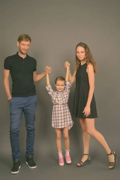 Young happy family bonding together against gray background — Stock Photo, Image