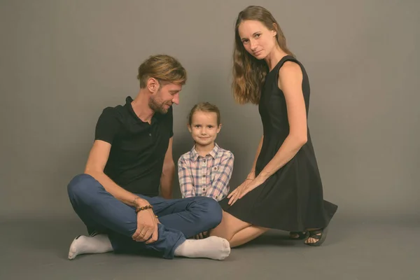 Jong gelukkig familie binding samen tegen grijs achtergrond — Stockfoto