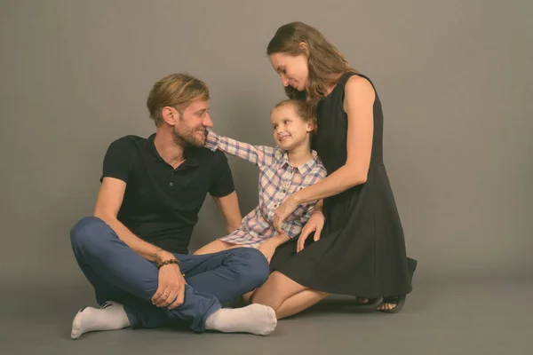 Jong gelukkig familie binding samen tegen grijs achtergrond — Stockfoto