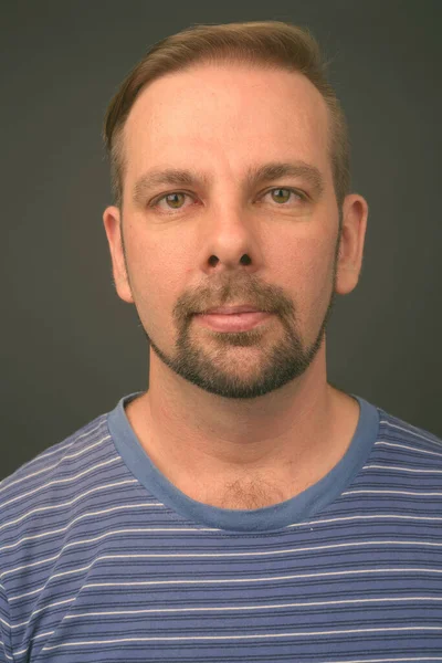 Blond bearded man with goatee against gray background