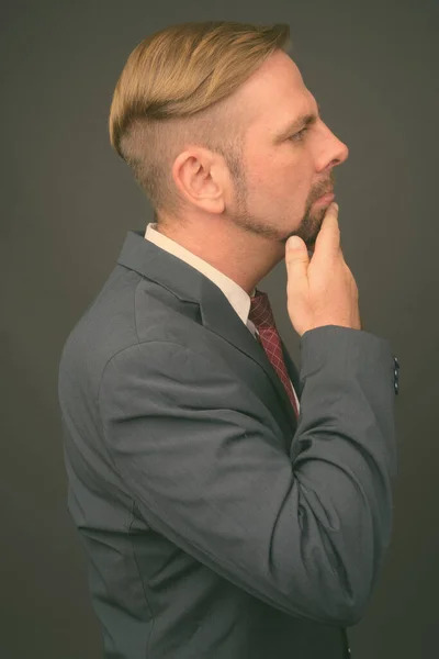 Светловолосый бизнесмен с козлиной бородкой на сером фоне — стоковое фото