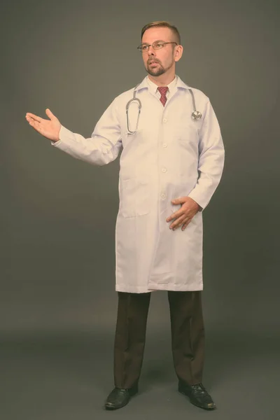 Блондинка бородатий чоловік лікар з ґоаті на сірому фоні — стокове фото