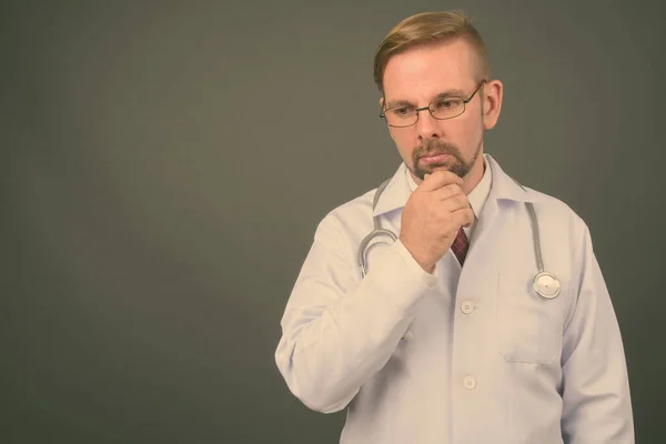 Hombre rubio barbudo médico con perilla sobre fondo gris — Foto de Stock