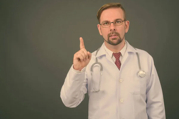 Hombre rubio barbudo médico con perilla sobre fondo gris — Foto de Stock