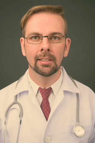 회색 배경에 염소가 있는 금발의 남자 의사 — 스톡 사진