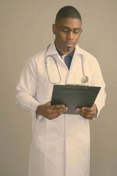 Joven guapo africano hombre médico contra gris fondo —  Fotos de Stock