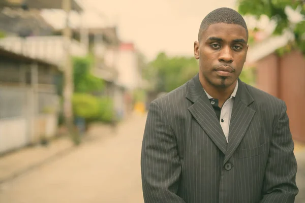 Young handsome African businessman wearing suit in the streets outdoors — Stock Photo, Image