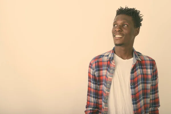 Studio ampui nuoren onnellisen mustan afrikkalaisen miehen hymyilemässä ja ajattelemassa katsellen valkoista taustaa vasten — kuvapankkivalokuva
