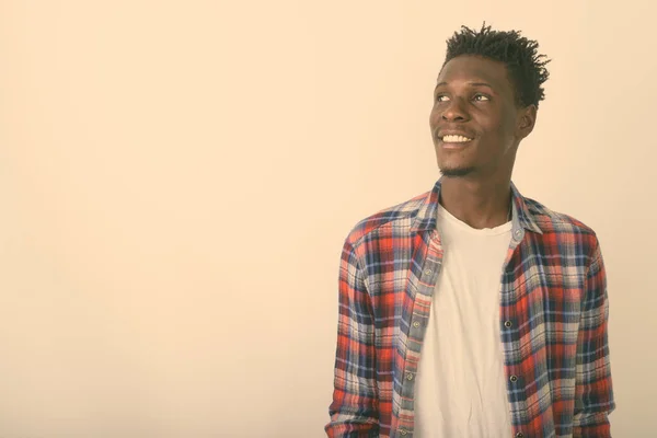 Estudio disparo de joven feliz negro africano hombre sonriendo y pensando mientras mira hacia arriba sobre fondo blanco — Foto de Stock