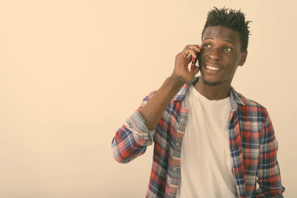 Close up de jovem negro feliz Africano homem sorrindo ao pensar e falar no telefone celular contra fundo branco — Fotografia de Stock